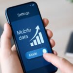 How to Improve Mobile Data Speeds, A person holding a smartphone outdoors with visible signal bars and digital network icons, representing mobile data and internet connectivity.